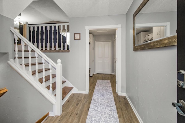 interior space featuring baseboards, a textured ceiling, and wood finished floors