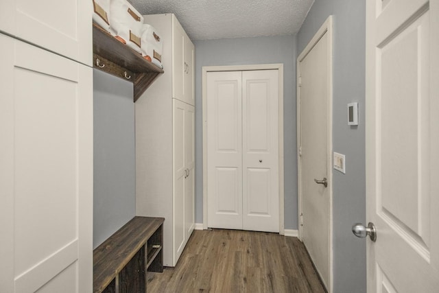 mudroom featuring a textured ceiling, dark wood finished floors, and baseboards