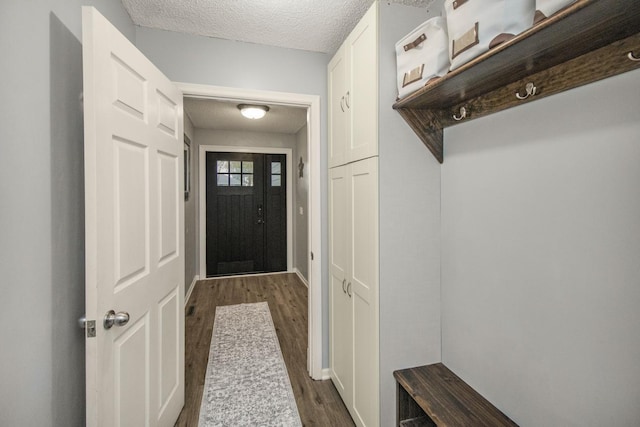 mudroom featuring baseboards, dark wood finished floors, and a textured ceiling