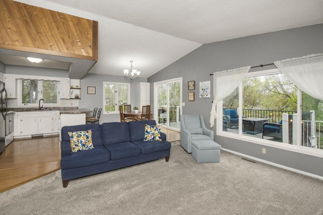 living area featuring dark carpet, plenty of natural light, a chandelier, and vaulted ceiling