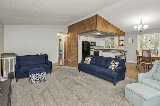 living area featuring baseboards, visible vents, wood walls, and a notable chandelier