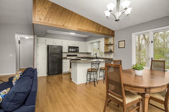 dining room with a notable chandelier, a wealth of natural light, light wood-style flooring, and vaulted ceiling
