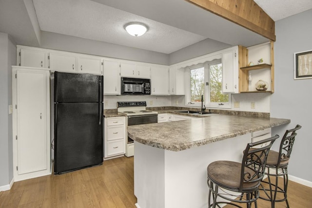kitchen with open shelves, light wood-type flooring, a sink, black appliances, and a peninsula