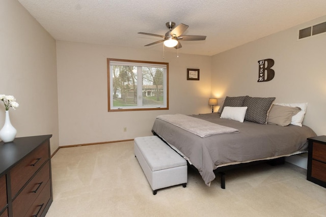 bedroom featuring a textured ceiling, light colored carpet, ceiling fan, and visible vents