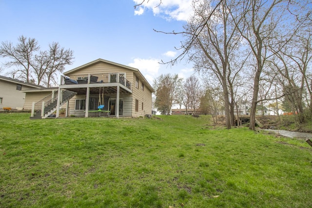 rear view of property with a deck, a yard, and stairway