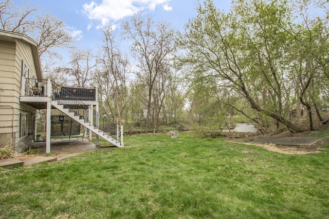 view of yard with a patio, a wooden deck, and stairs