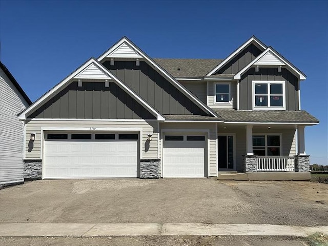 craftsman-style house with an attached garage, board and batten siding, covered porch, and stone siding