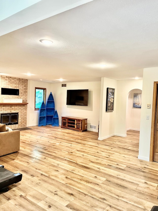 655 Trails End Rd, Minnetrista, MN 55364 - unfurnished living room featuring light wood-style floors, arched walkways, baseboards, and a fireplace