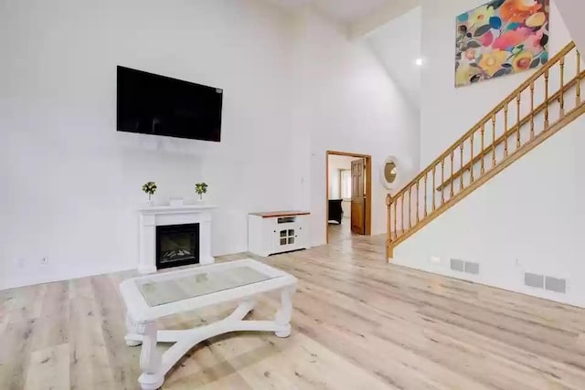 655 Trails End Rd, Minnetrista, MN 55364 - living room with stairway, wood finished floors, a high ceiling, and a glass covered fireplace