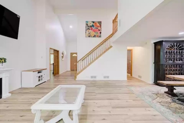 655 Trails End Rd, Minnetrista, MN 55364 - unfurnished living room with stairs, a towering ceiling, light wood-style floors, and recessed lighting