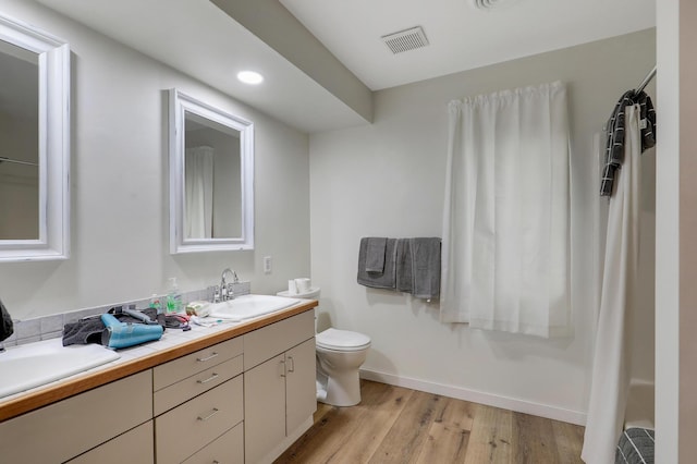 655 Trails End Rd, Minnetrista, MN 55364 - bathroom with double vanity, wood finished floors, toilet, baseboards, and recessed lighting
