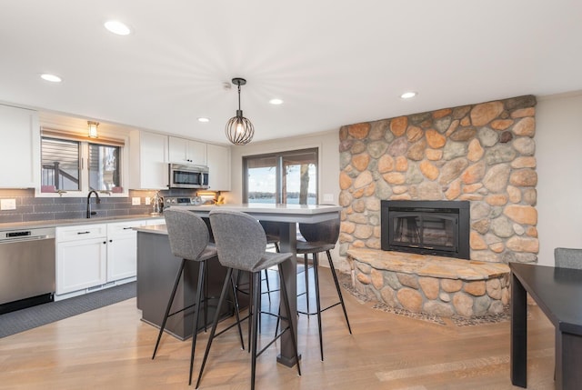 3008 Highland Blvd, Mound, MN 55364 - kitchen featuring appliances with stainless steel finishes, white cabinetry, a breakfast bar area, light wood finished floors, and decorative backsplash