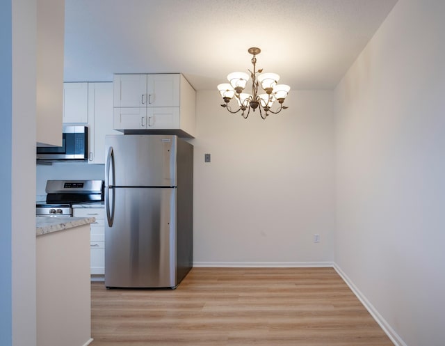 kitchen featuring light wood-type flooring, a notable chandelier, white cabinets, and stainless steel appliances