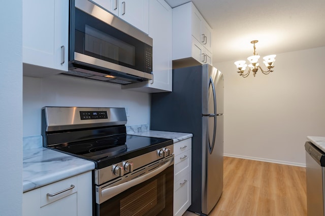 2446 Aldrich Ave S Unit 111, Minneapolis, MN 55405 - kitchen featuring stainless steel appliances, light wood-style floors, a chandelier, white cabinets, and hanging light fixtures