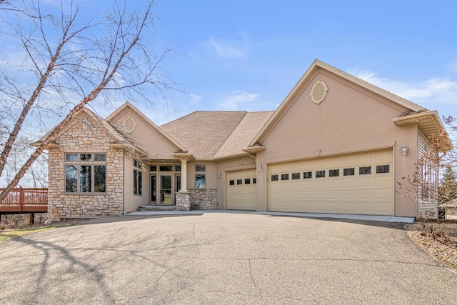 view of front of property with an attached garage, aphalt driveway, stone siding, and stucco siding