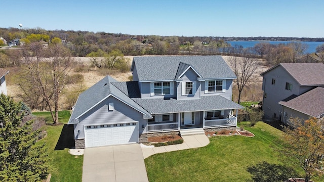 traditional-style home with covered porch, a shingled roof, driveway, a front lawn, and an attached garage