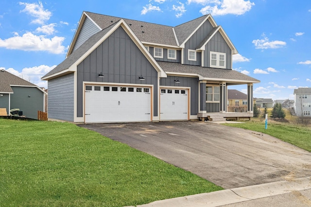 view of front of home featuring roof with shingles, board and batten siding, aphalt driveway, a front yard, and covered porch