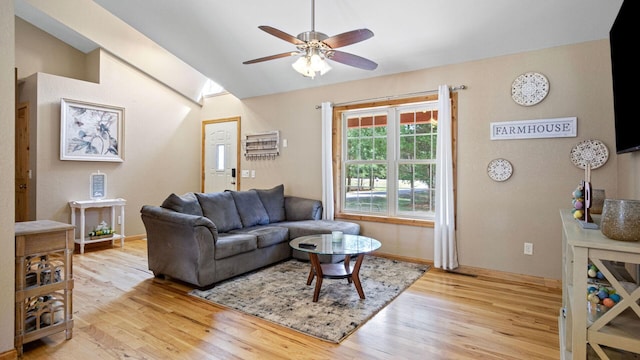 living area with baseboards, light wood-type flooring, vaulted ceiling, and ceiling fan