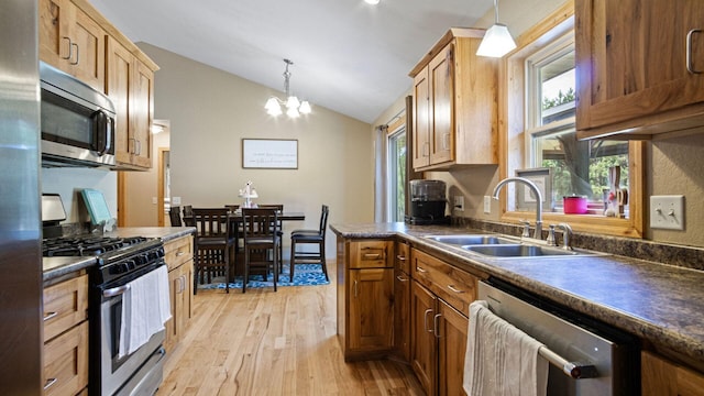 kitchen with dark countertops, lofted ceiling, a sink, and appliances with stainless steel finishes