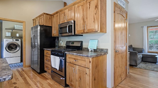 kitchen with washer / clothes dryer, light wood-style flooring, dark countertops, and stainless steel appliances
