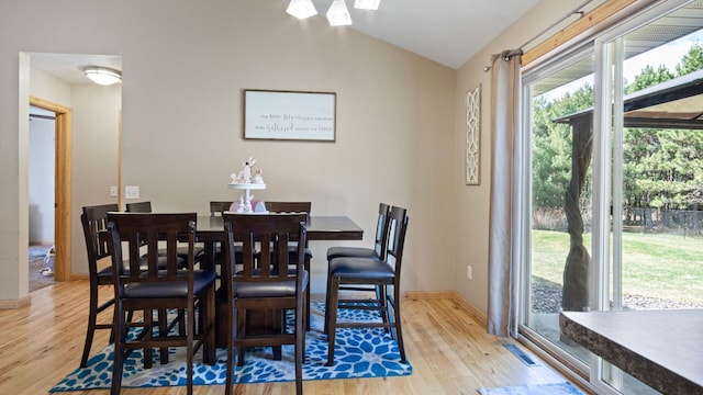 dining room featuring visible vents, baseboards, wood finished floors, and vaulted ceiling