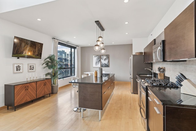 3104 Lake St Unit 410, Minneapolis, MN 55416 - kitchen featuring stainless steel appliances, a kitchen island, decorative backsplash, light wood-type flooring, and a breakfast bar