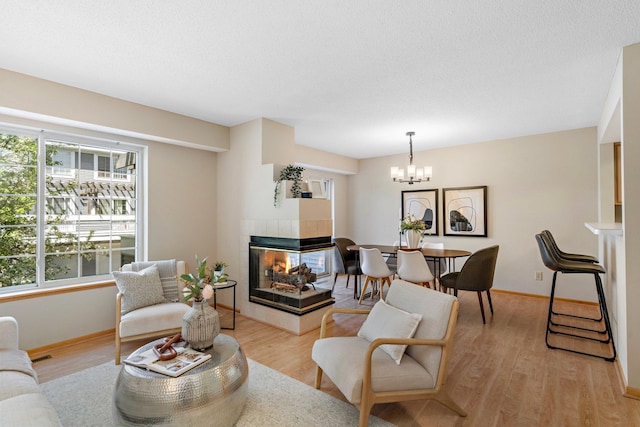 15625 24th Ave N Unit G, Plymouth, MN 55447 - living area with a chandelier, a tiled fireplace, light wood-style floors, and baseboards