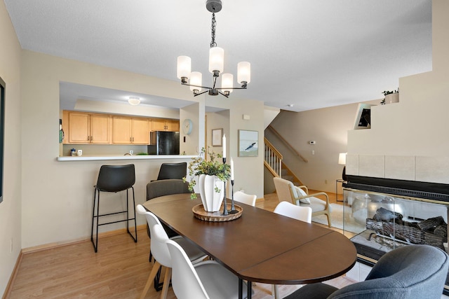 15625 24th Ave N Unit G, Plymouth, MN 55447 - dining space with a chandelier, stairs, light wood-style flooring, baseboards, and a tile fireplace