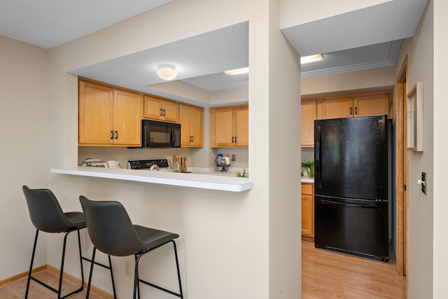 15625 24th Ave N Unit G, Plymouth, MN 55447 - kitchen with black appliances, light countertops, light wood finished floors, a breakfast bar area, and baseboards