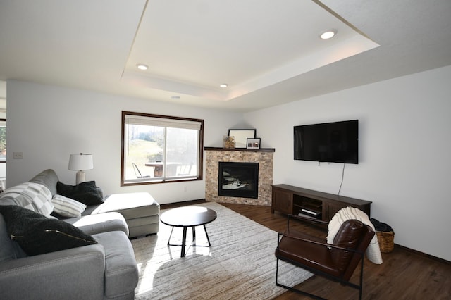 living room with a tray ceiling, baseboards, recessed lighting, and wood finished floors
