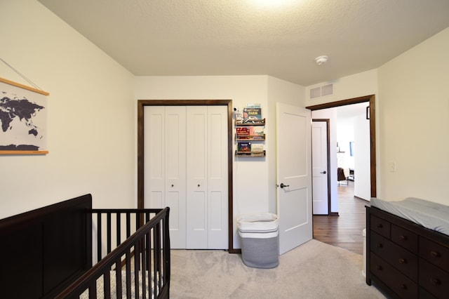 bedroom featuring visible vents, a closet, carpet floors, and a textured ceiling