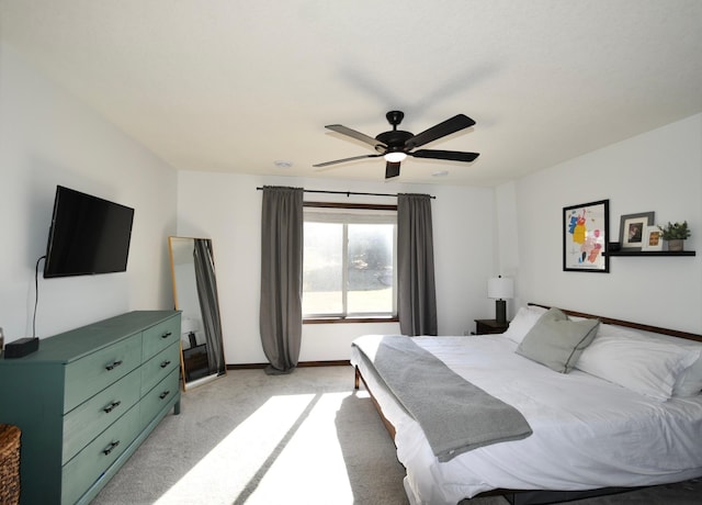 bedroom with light colored carpet, baseboards, and a ceiling fan