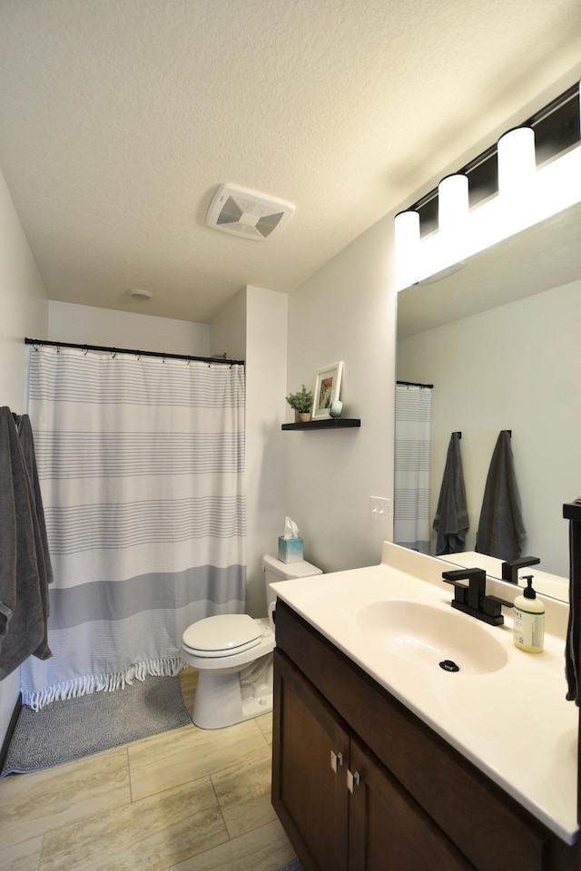 bathroom featuring a textured ceiling, vanity, visible vents, toilet, and wood finished floors