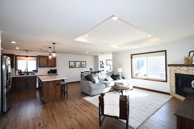 living room with recessed lighting, dark wood-type flooring, and a raised ceiling