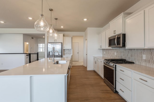 kitchen featuring an island with sink, recessed lighting, appliances with stainless steel finishes, a sink, and decorative backsplash