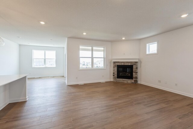 unfurnished living room with recessed lighting, a fireplace, baseboards, and wood finished floors