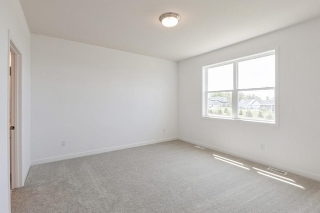 spare room with carpet flooring, visible vents, and baseboards