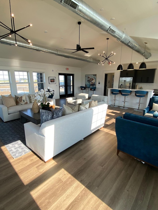 living area featuring wood finished floors, ceiling fan with notable chandelier, a high ceiling, and visible vents