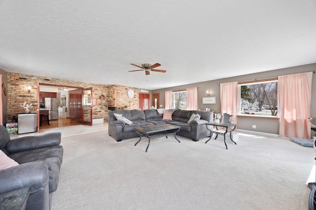 carpeted living area with a ceiling fan, a textured ceiling, and brick wall