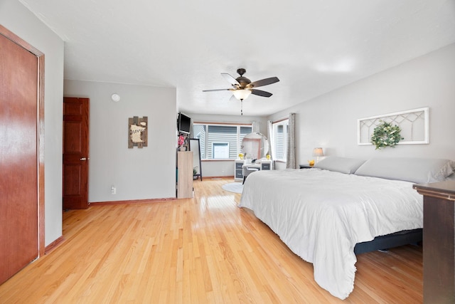 bedroom with baseboards, ceiling fan, and light wood-style flooring