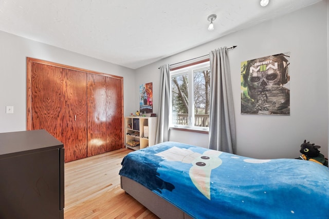 bedroom with light wood finished floors and a closet