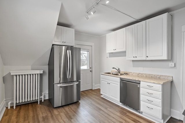 kitchen with radiator, stainless steel appliances, light countertops, track lighting, and a sink