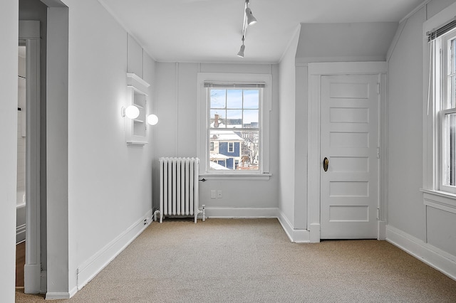 interior space featuring radiator, carpet flooring, baseboards, and rail lighting