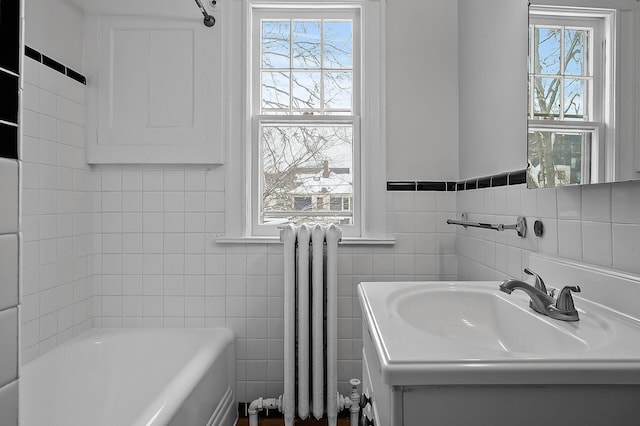 full bath with tile walls, a bath, radiator, and a wealth of natural light