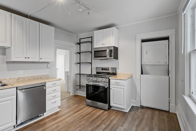 kitchen with dark wood-style floors, stacked washer / dryer, white cabinetry, and appliances with stainless steel finishes
