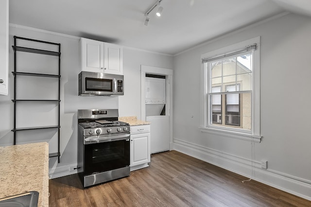 kitchen featuring dark wood-style flooring, stacked washer and dryer, track lighting, white cabinets, and stainless steel appliances