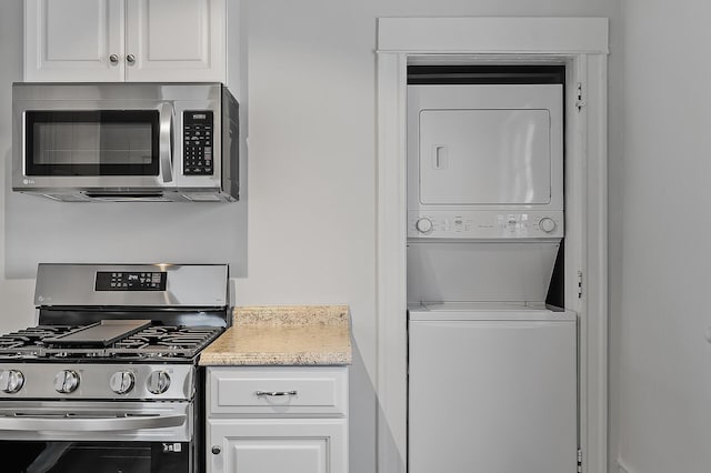 kitchen with white cabinets, appliances with stainless steel finishes, and stacked washer / drying machine