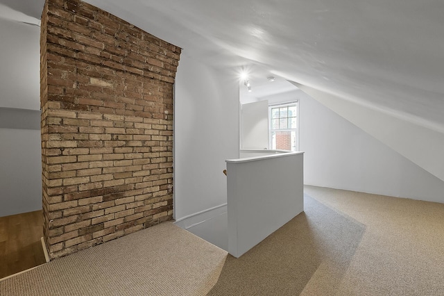 bonus room with brick wall, vaulted ceiling, and carpet