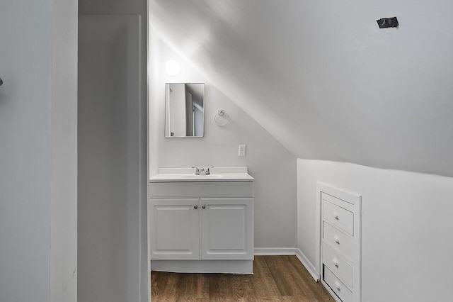 bathroom with vaulted ceiling, wood finished floors, and vanity