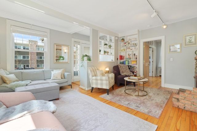 living room featuring track lighting, baseboards, hardwood / wood-style floors, and built in shelves
